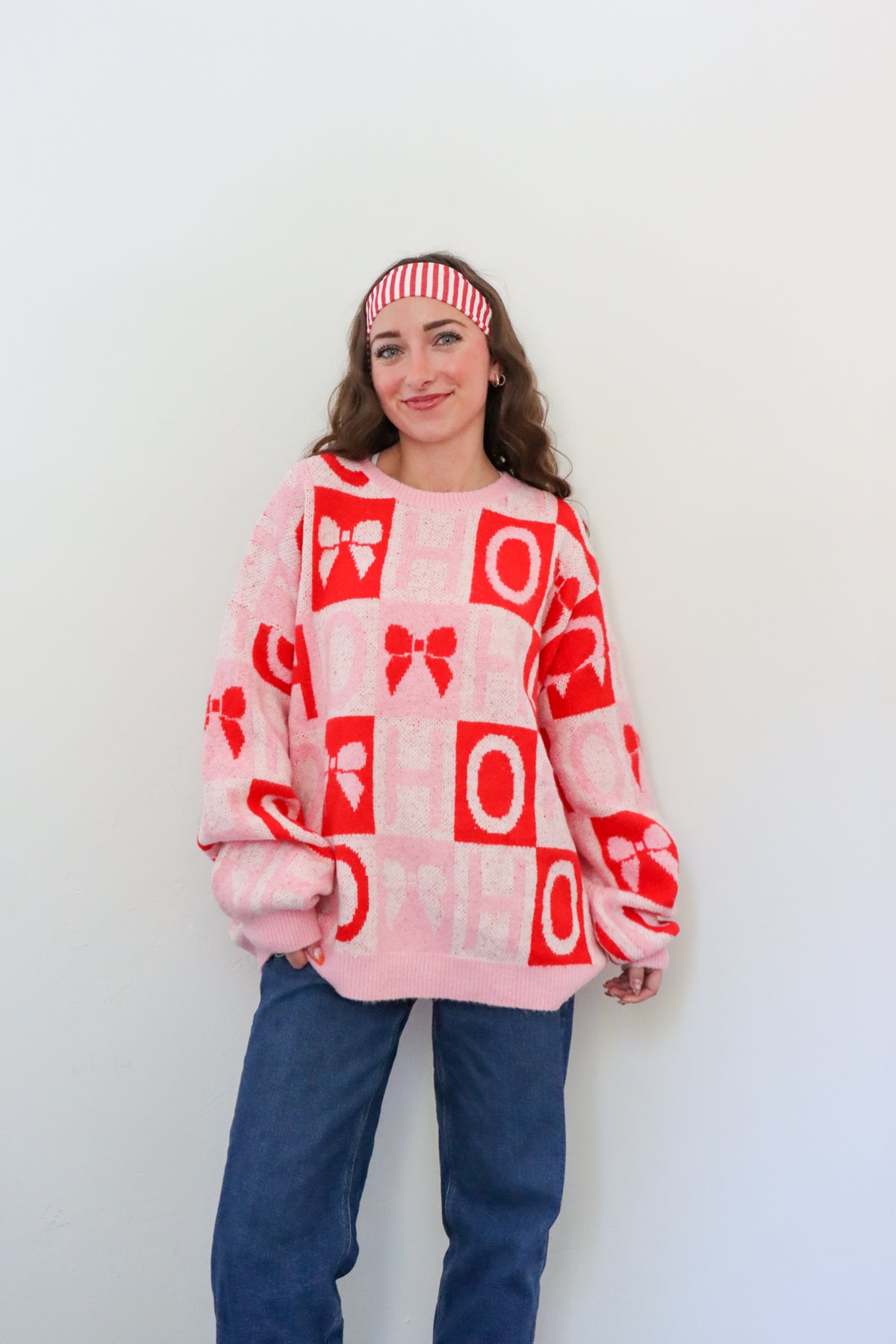 Person wearing a pink sweater with red patterns against a white background