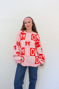 Person wearing a pink sweater with red patterns against a white background