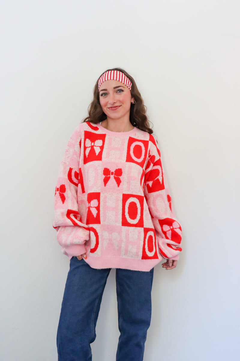 Person wearing a pink sweater with red patterns against a white background