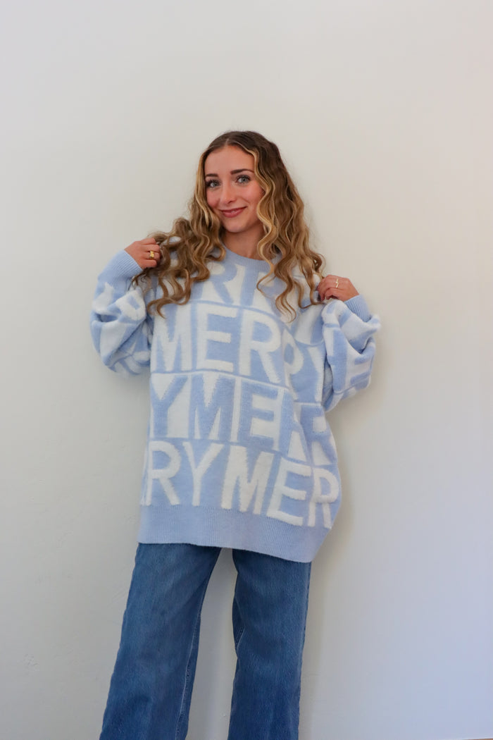 Person wearing a light blue sweater with 'Merry' text against a white background