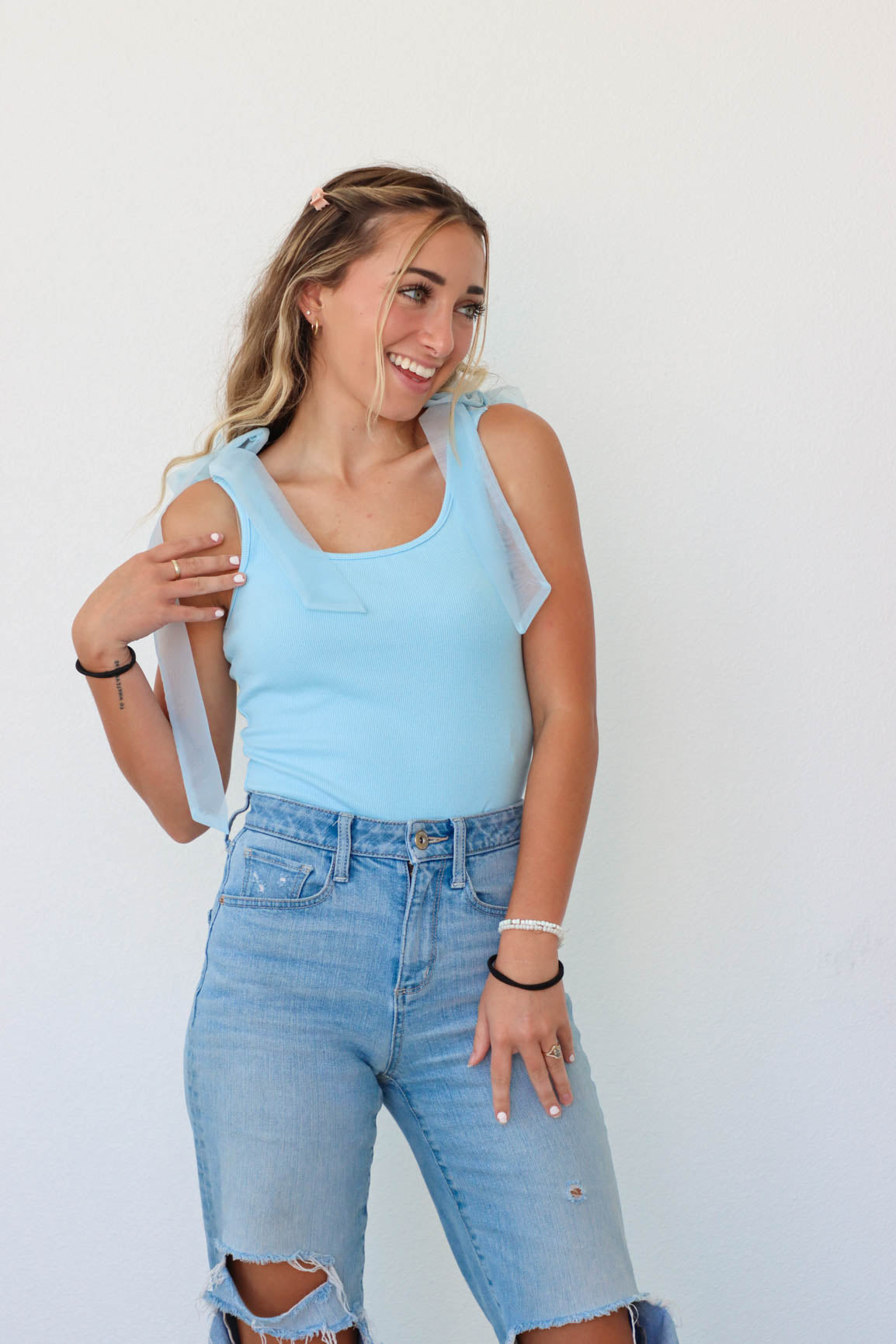 girl wearing light blue tank top bodysuit with tulle straps