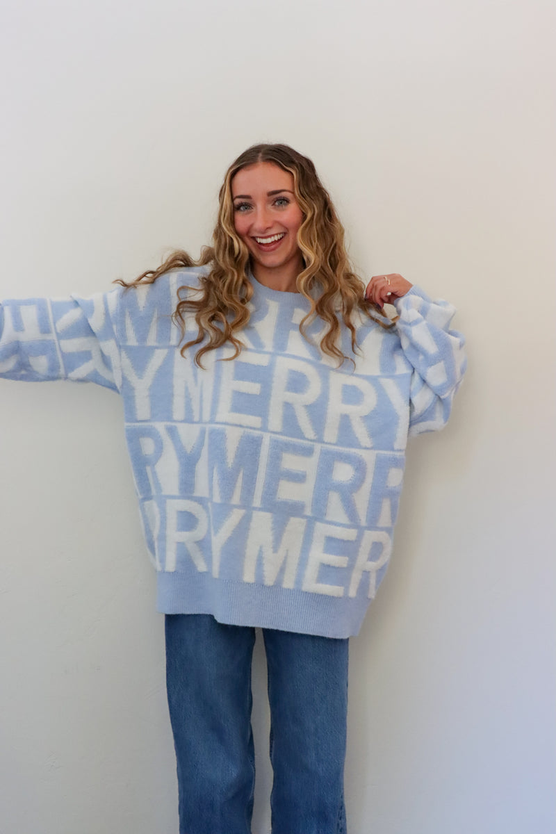Person wearing a light blue sweater with 'Merry' text against a white background