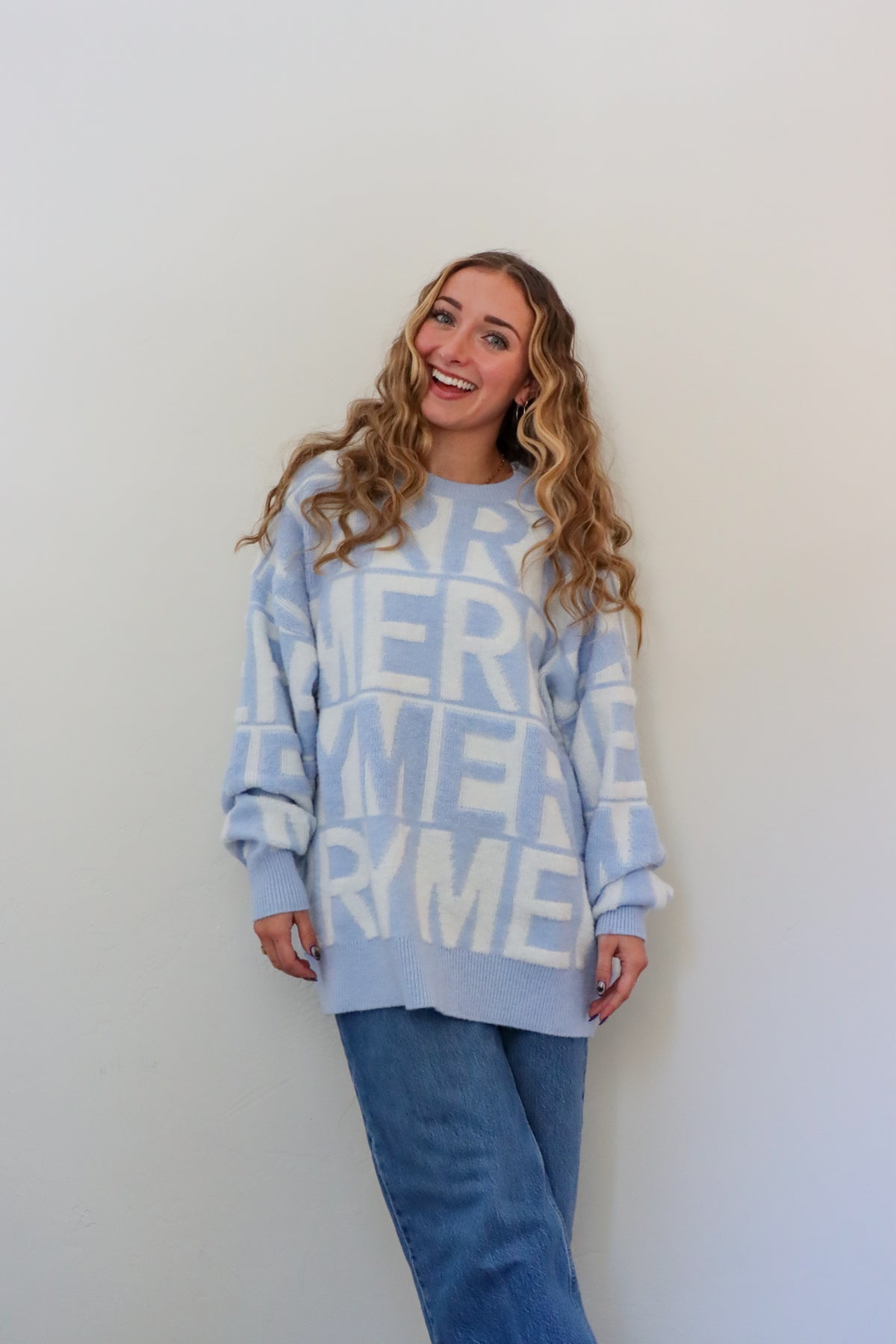 Woman wearing a light blue sweater with text pattern against a white background