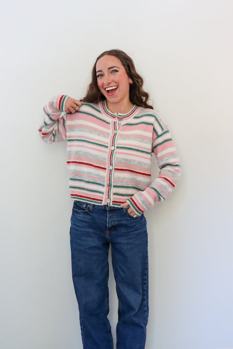 Person wearing a striped cardigan and blue jeans against a white background