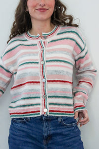 Person wearing a striped sweater and blue jeans against a white background