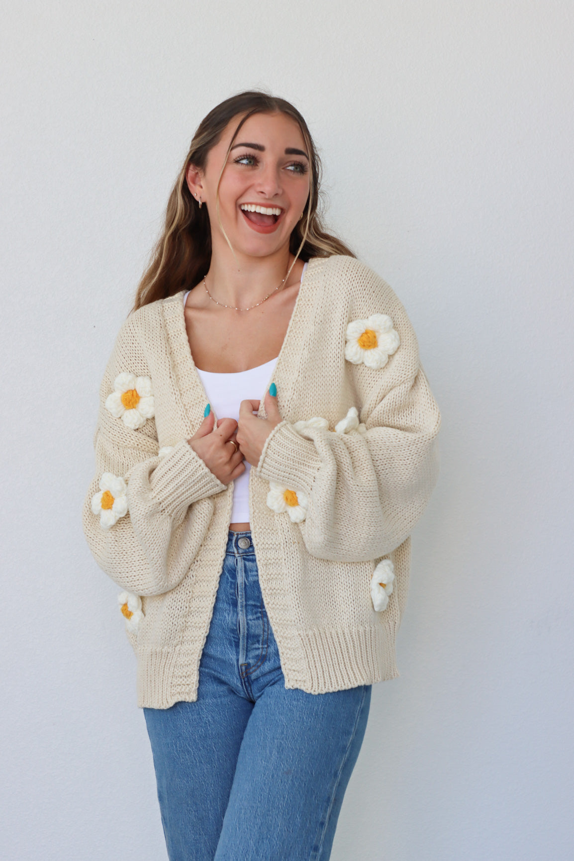 girl wearing cream knit cardigan with daisies
