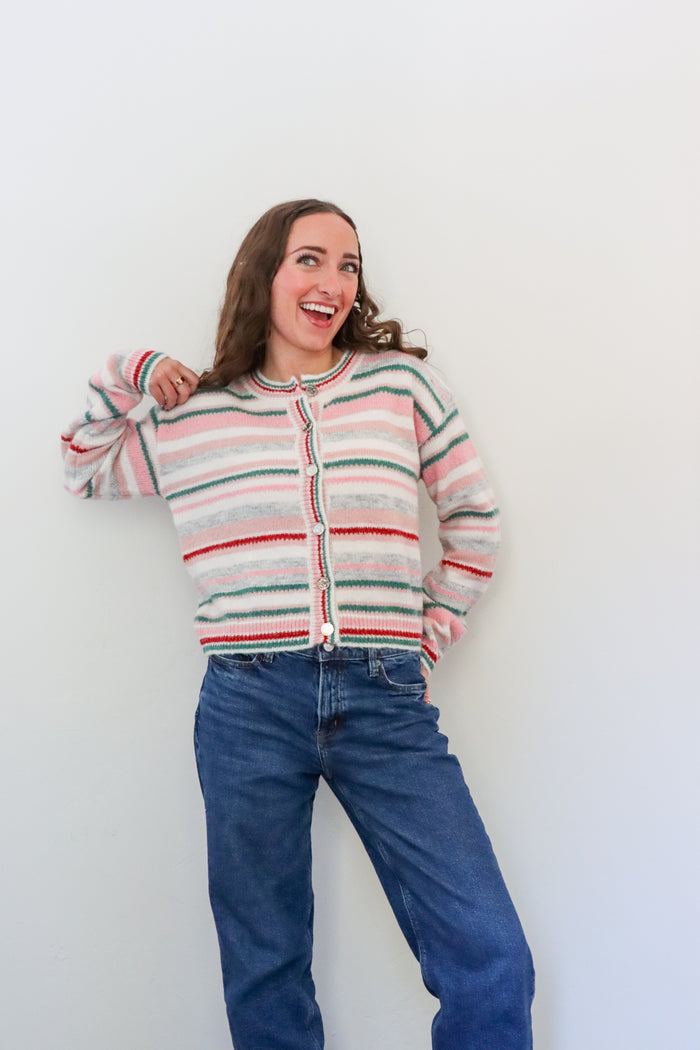 Person wearing a striped sweater and blue jeans against a white background