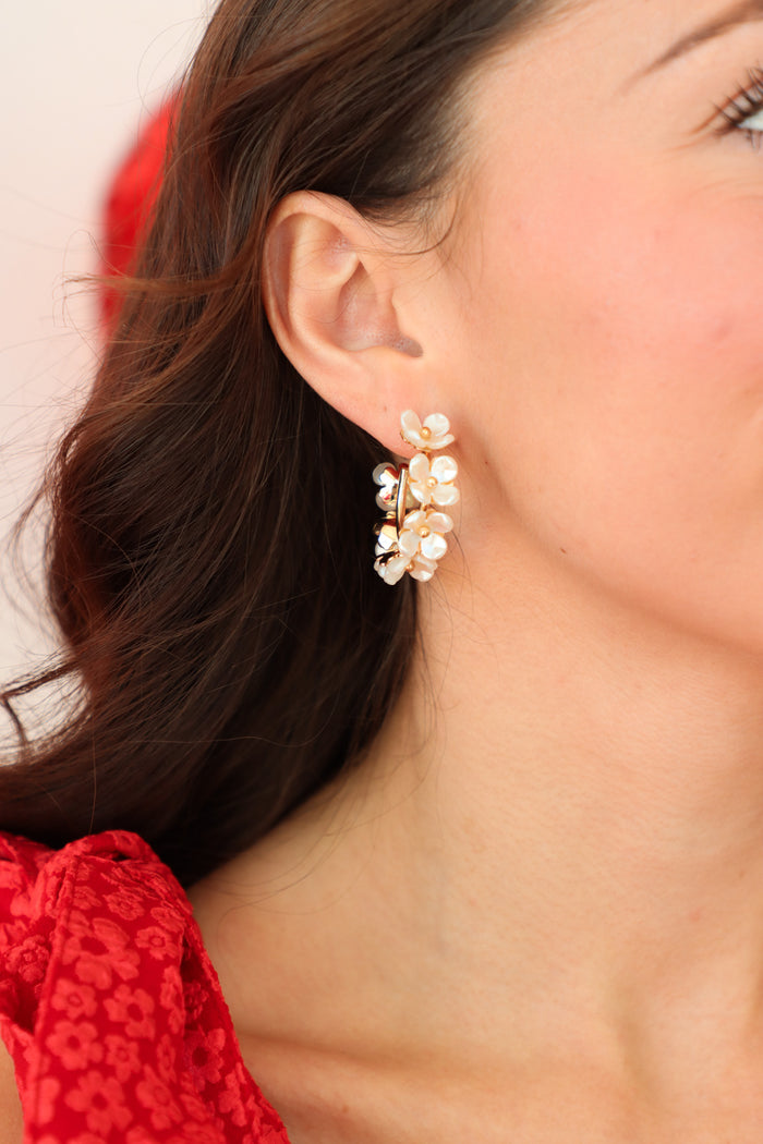 girl wearing white floral hoop earrings with gold detailing