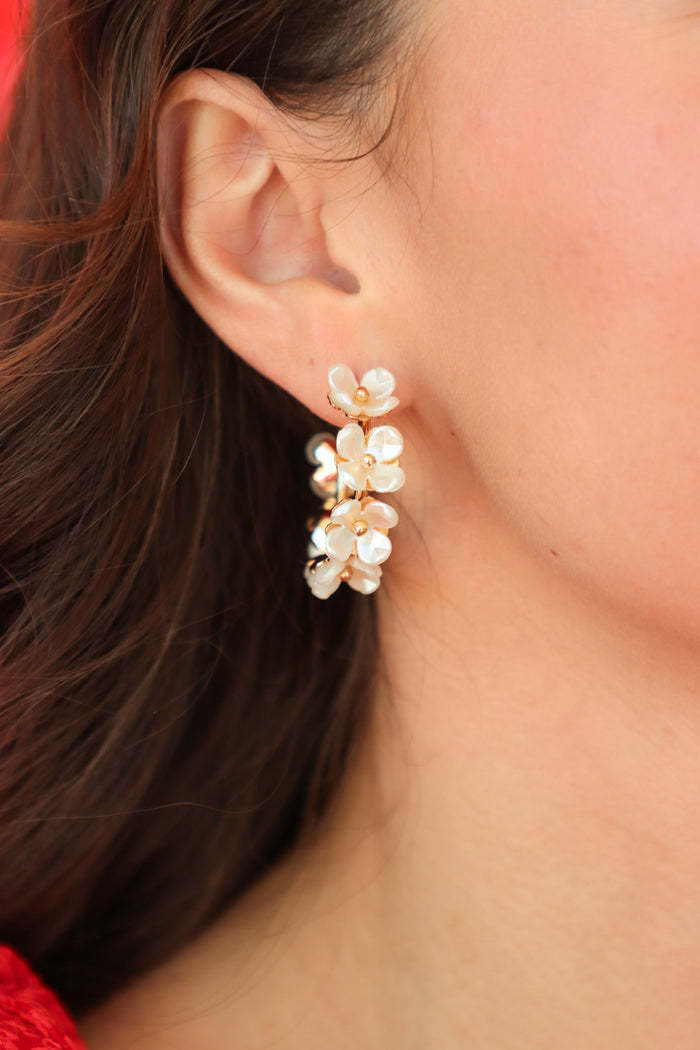 girl wearing white floral hoop earrings with gold detailing