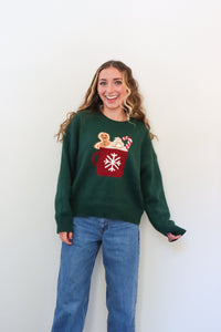 Person wearing a green sweater with a festive design against a white background