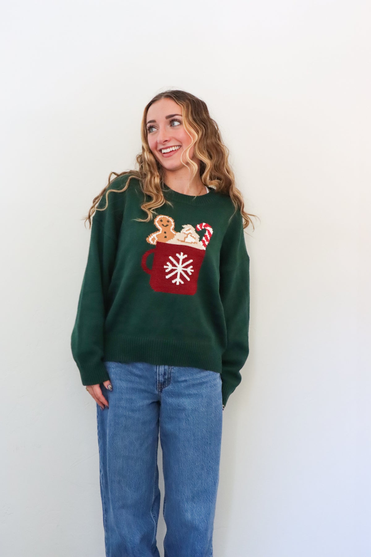 girl wearing dark green knit sweater with hot cocoa graphic