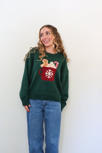 girl wearing dark green knit sweater with hot cocoa graphic