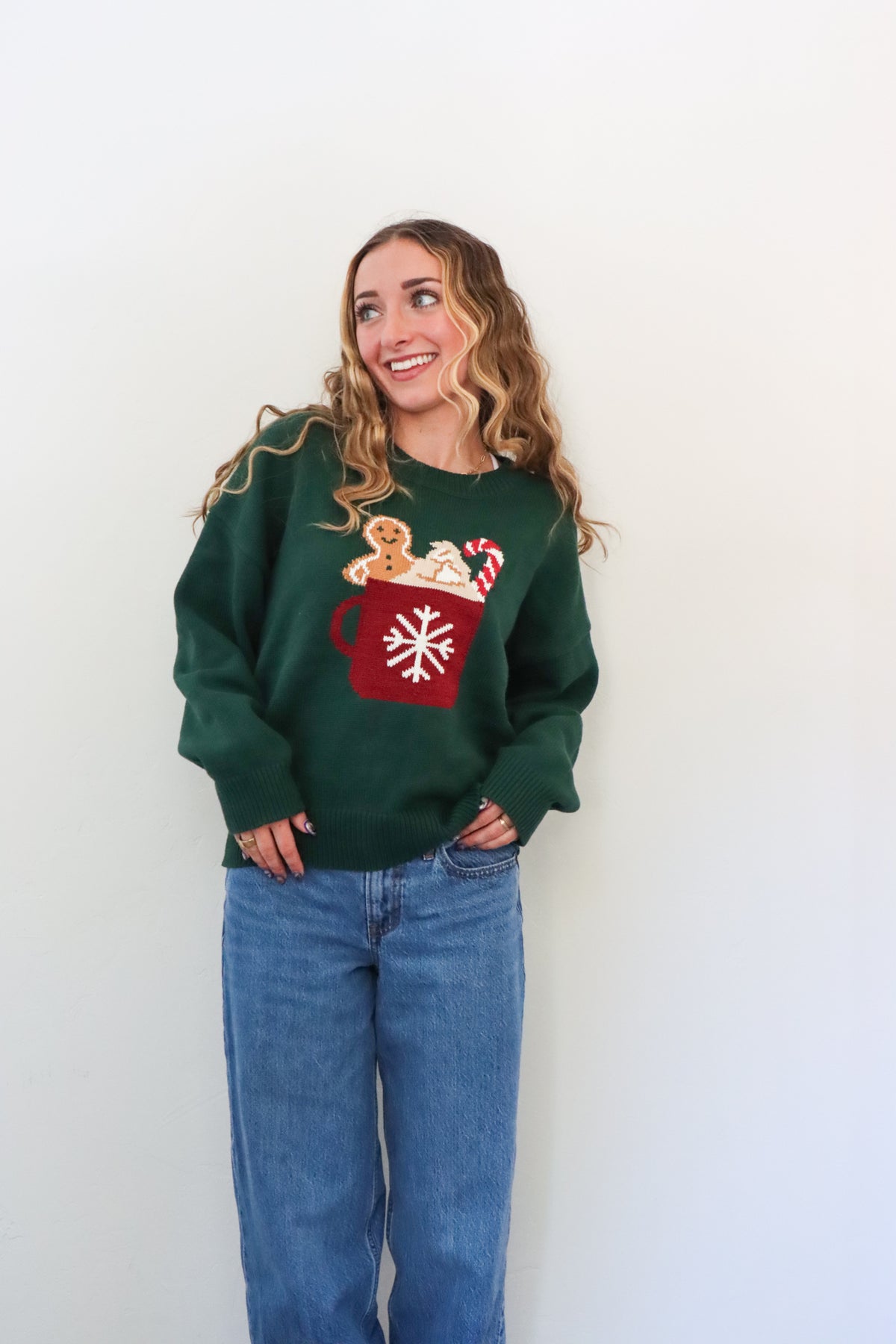 girl wearing dark green knit sweater with hot cocoa graphic