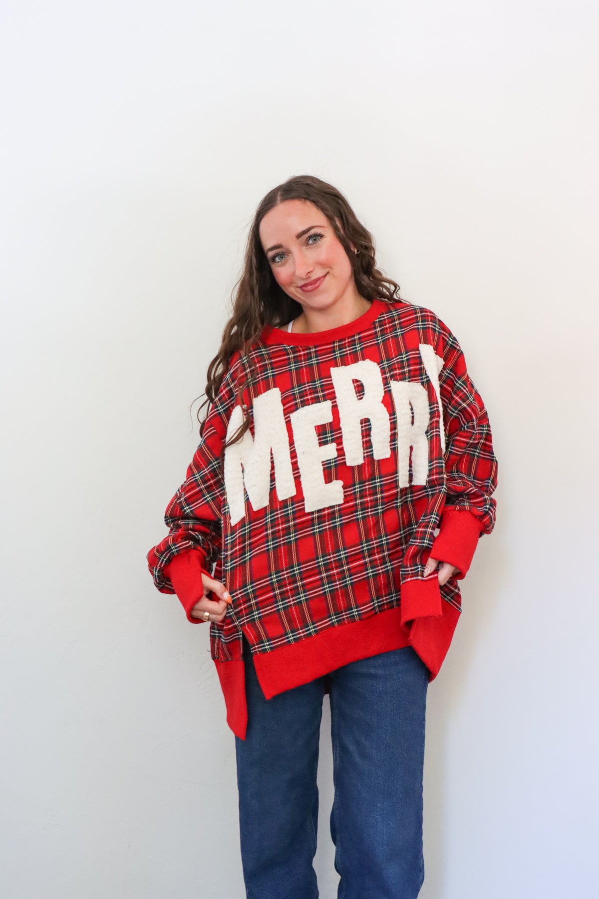 Person wearing a red plaid sweater with 'MERRY' text against a white background