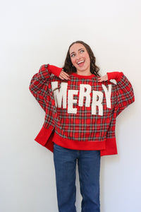 Person wearing a red plaid sweater with 'MERRY' text on a white background