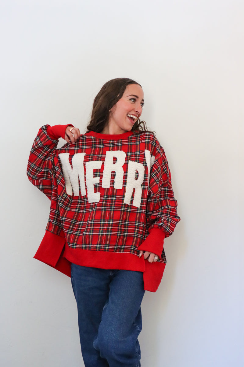 Person wearing a red plaid sweater with 'MERRY' text against a white background