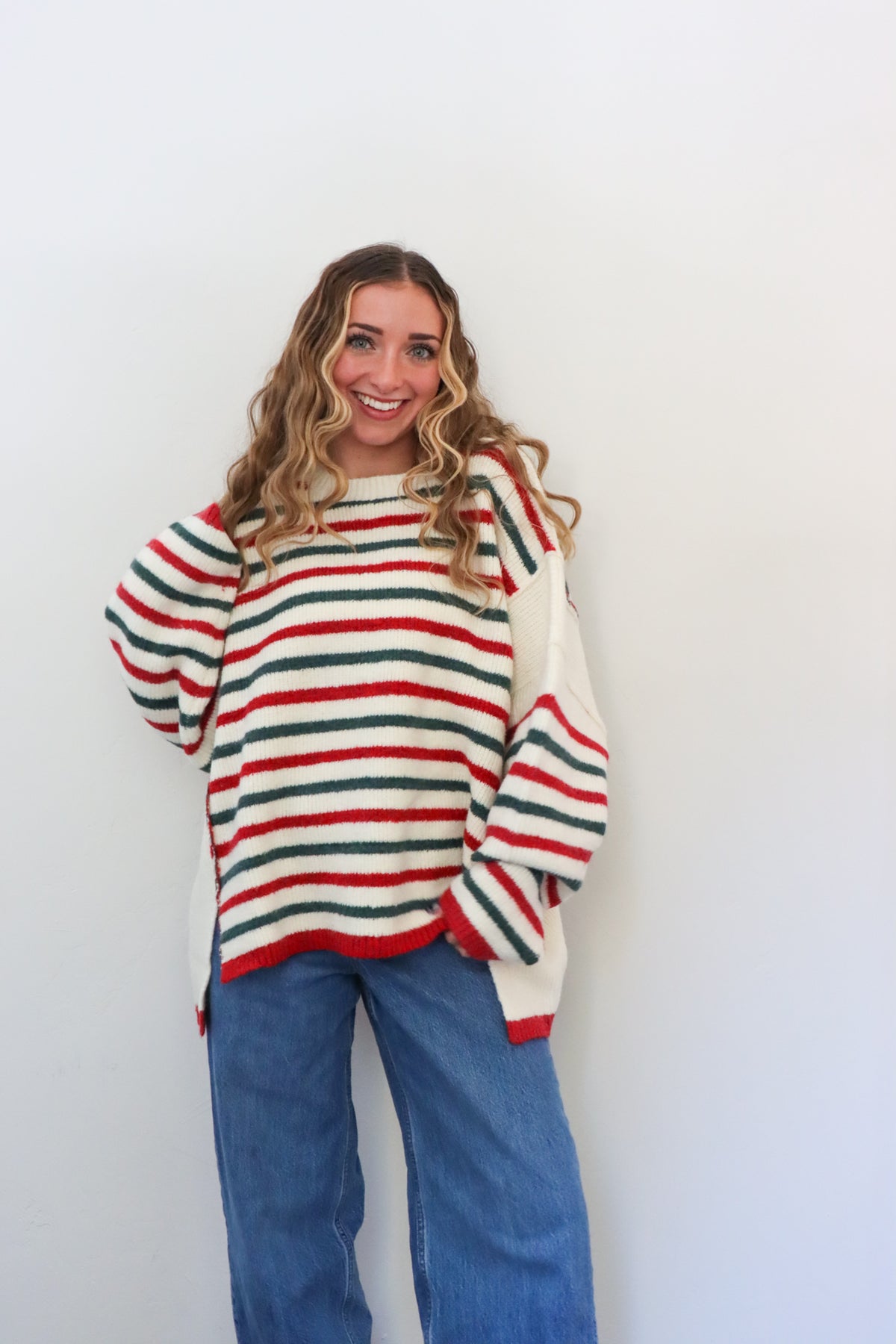Woman wearing a striped sweater and blue jeans against a white background
