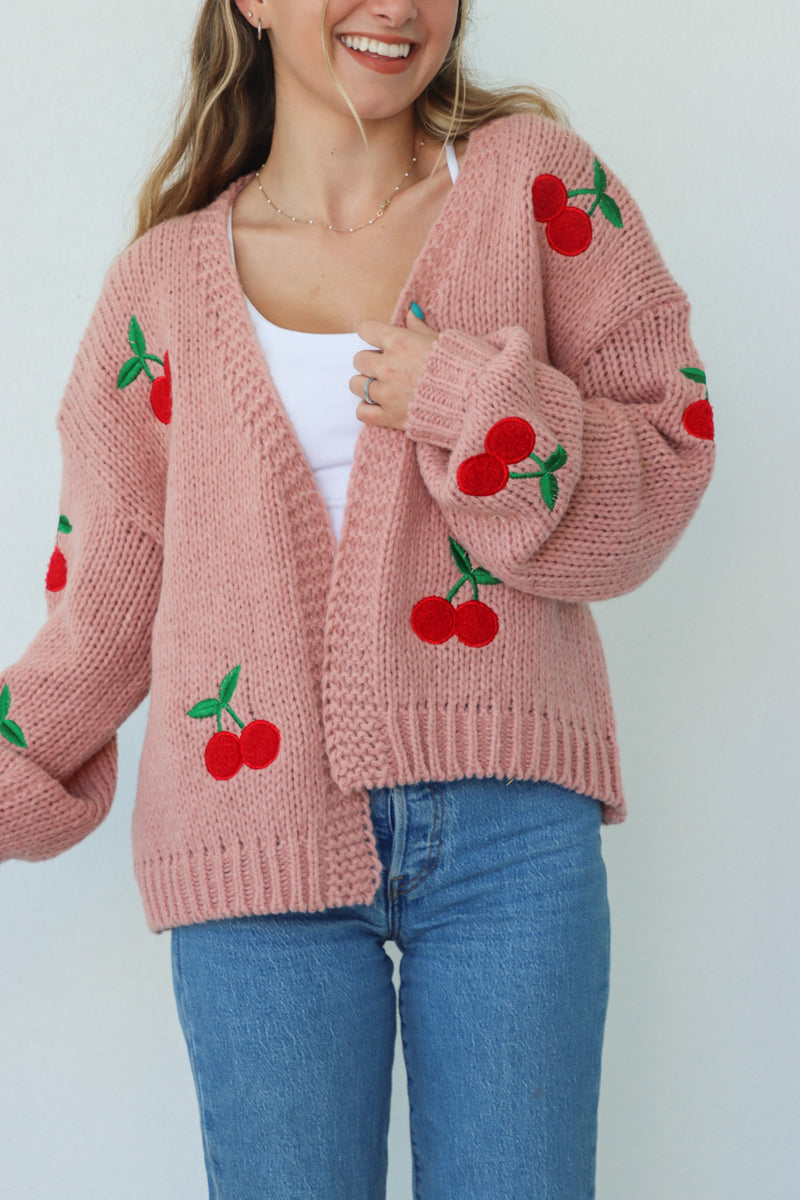 girl wearing pink knit cardigan with cherries