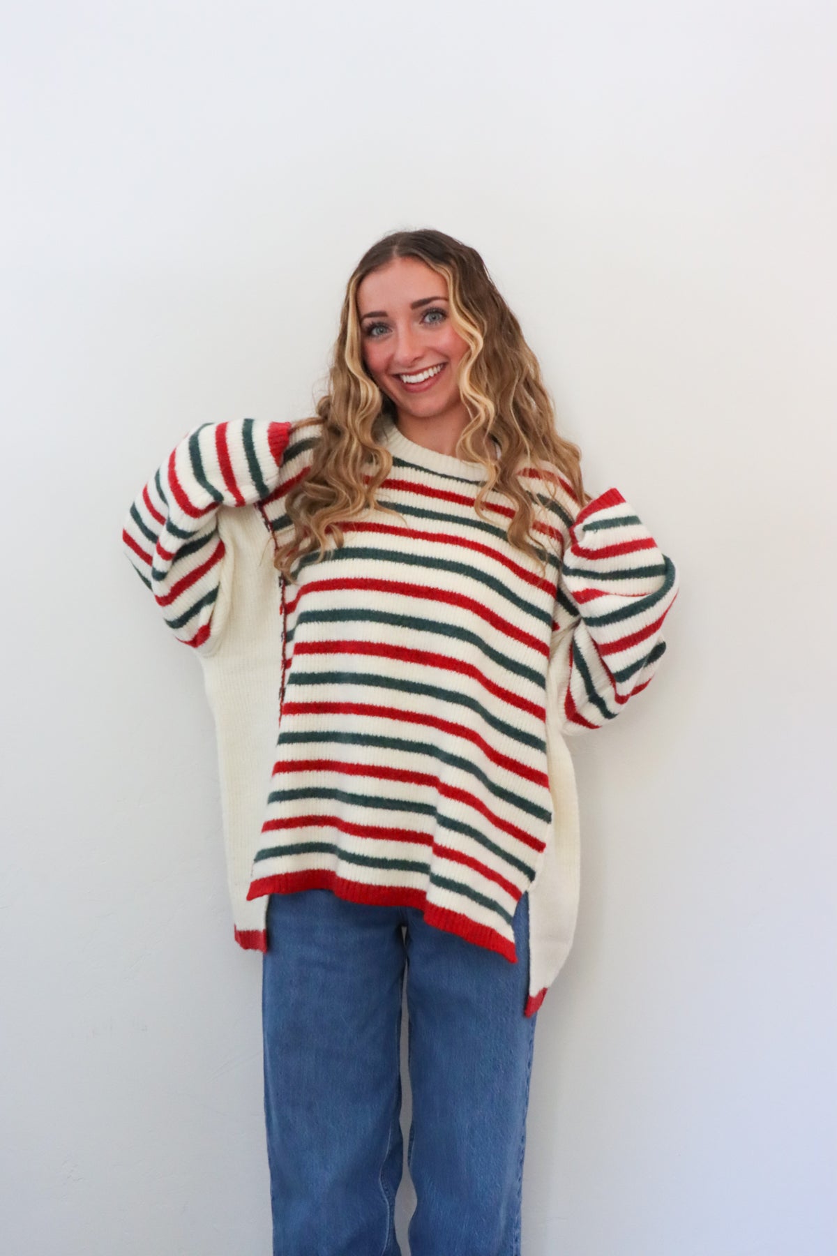 Woman wearing a striped sweater and blue jeans against a white background