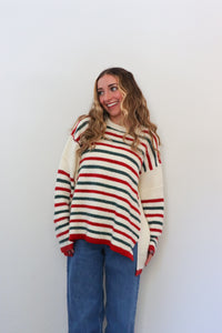 Woman wearing a striped sweater and blue jeans against a white background