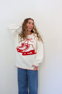 Woman wearing a white sweater with red ice skate design against a white background