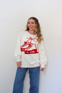 Woman wearing a white sweater with red ice skate design against a white background