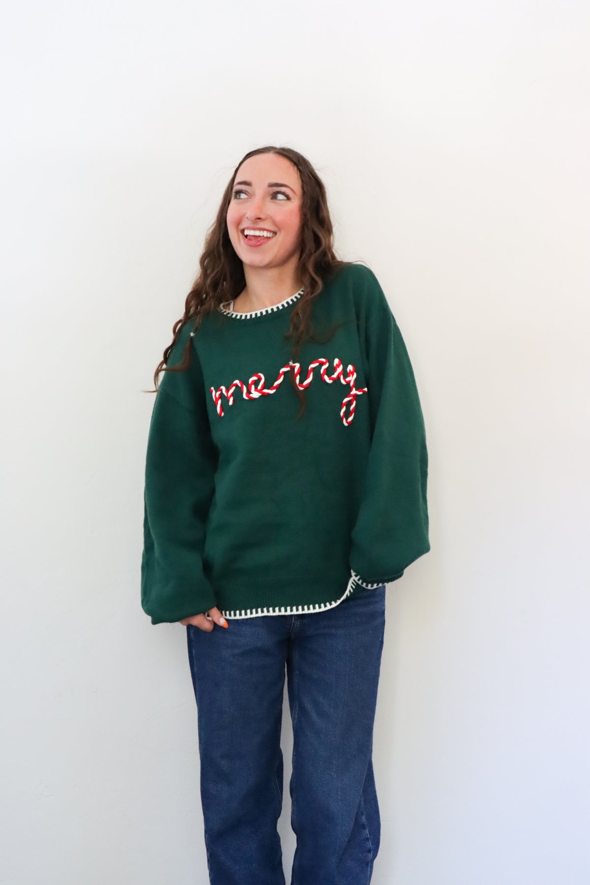 Woman wearing a green sweater with text, standing against a white background