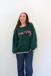 Woman wearing a green sweater with text, standing against a white background