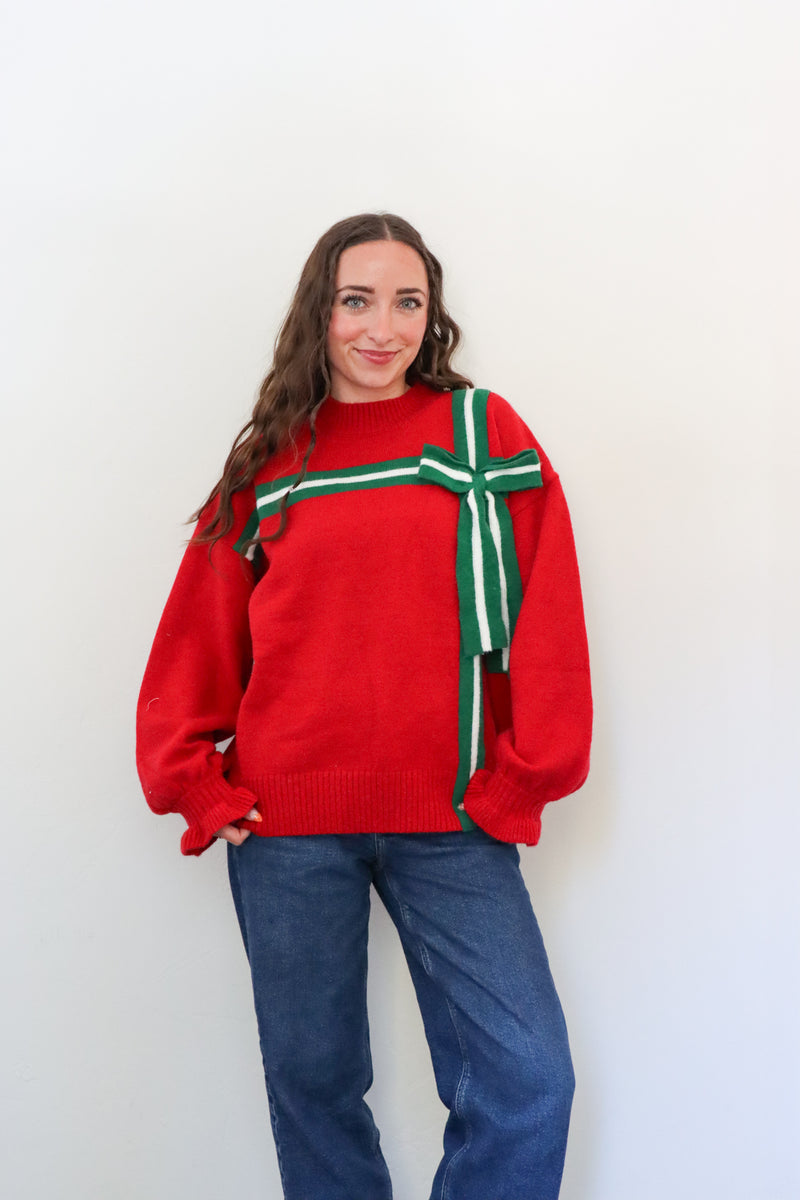 Person wearing a red sweater with green and white stripes against a white background