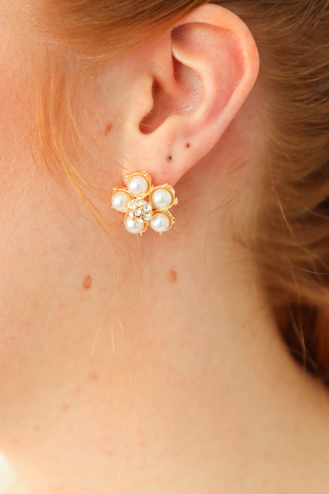 girl wearing gold daisy shaped earrings with pearl and rhinestone detailing