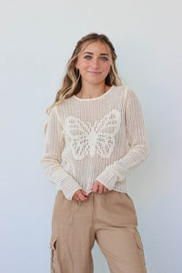 girl wearing cream crochet butterfly long sleeve top
