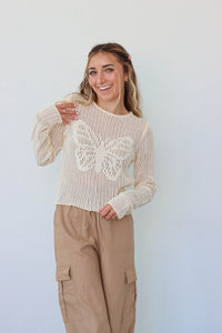 girl wearing cream crochet butterfly long sleeve top