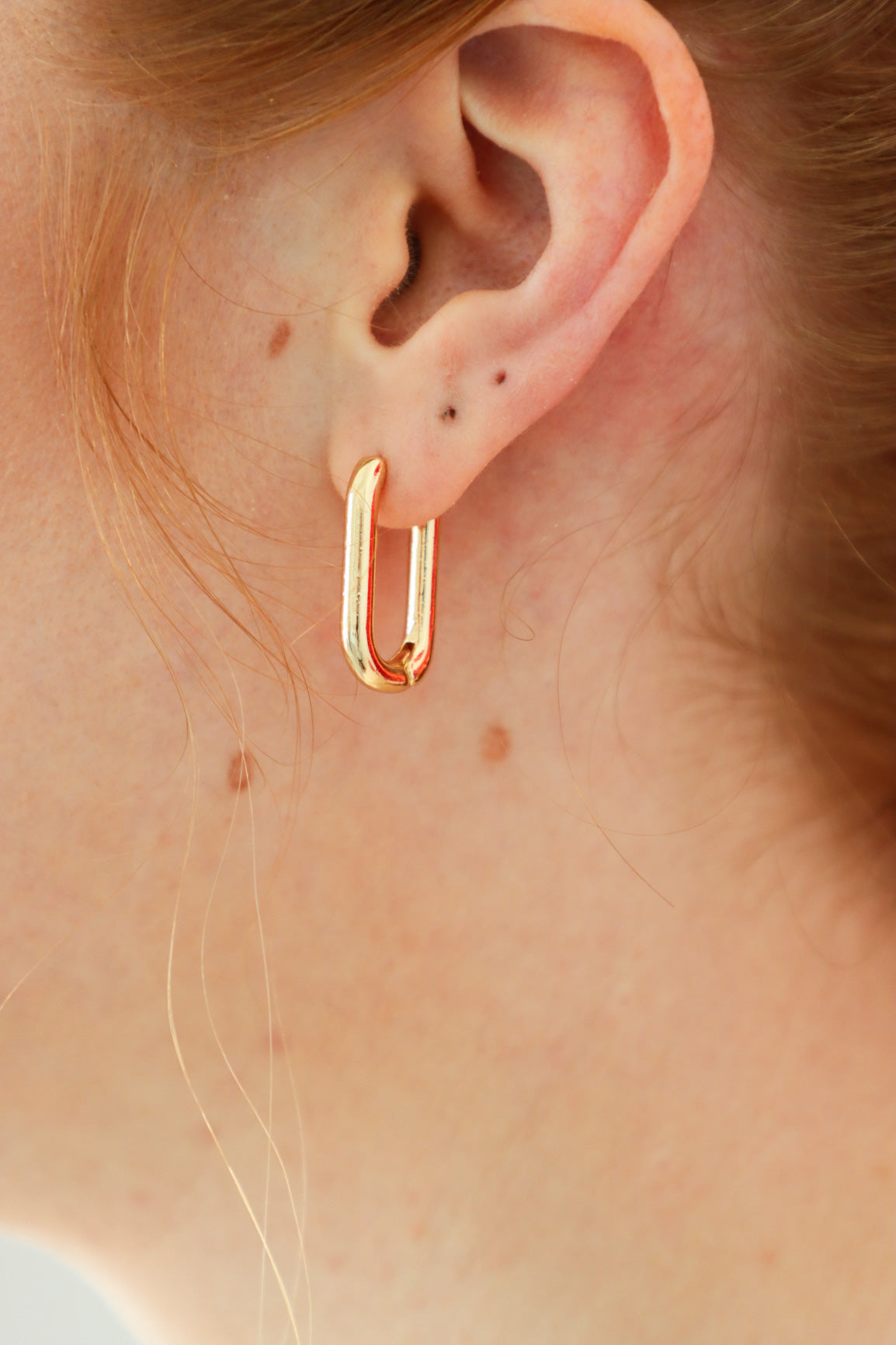 girl wearing gold huggie hoop earrings