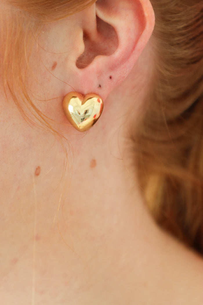 girl wearing gold heart-shaped stud earrings