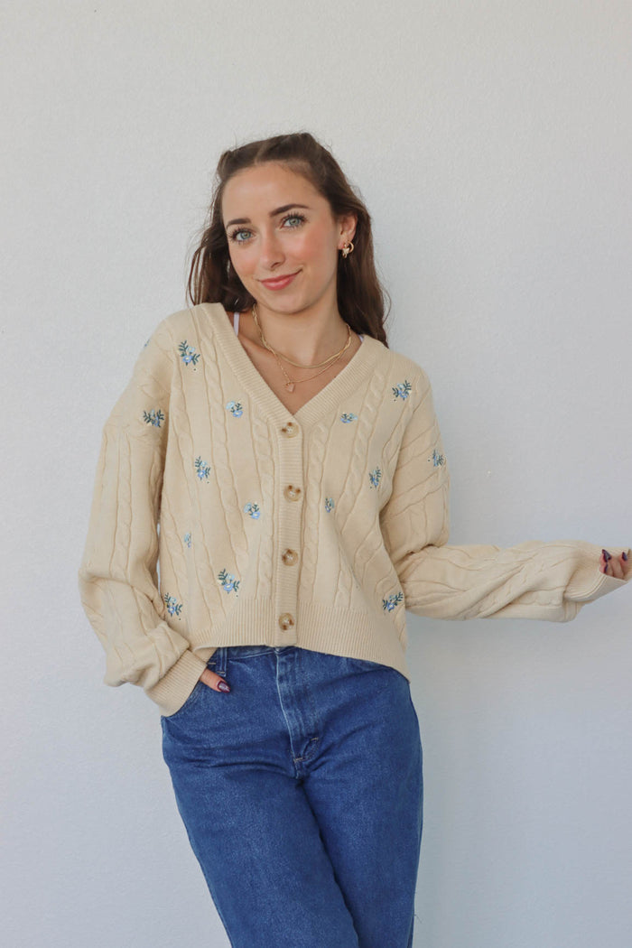 girl wearing cream knit cardigan with blue embroidered flowers