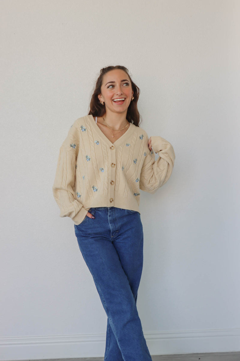 girl wearing cream knit cardigan with blue embroidered flowers