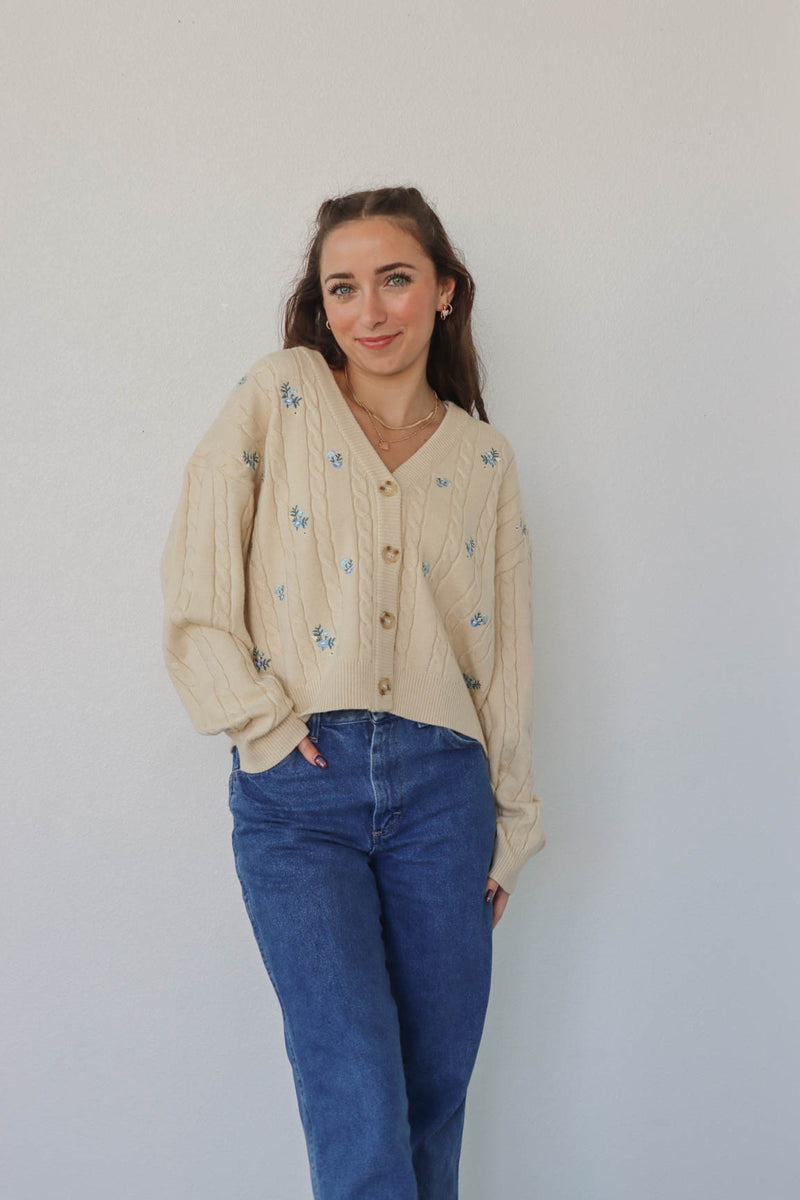 girl wearing cream knit cardigan with blue embroidered flowers