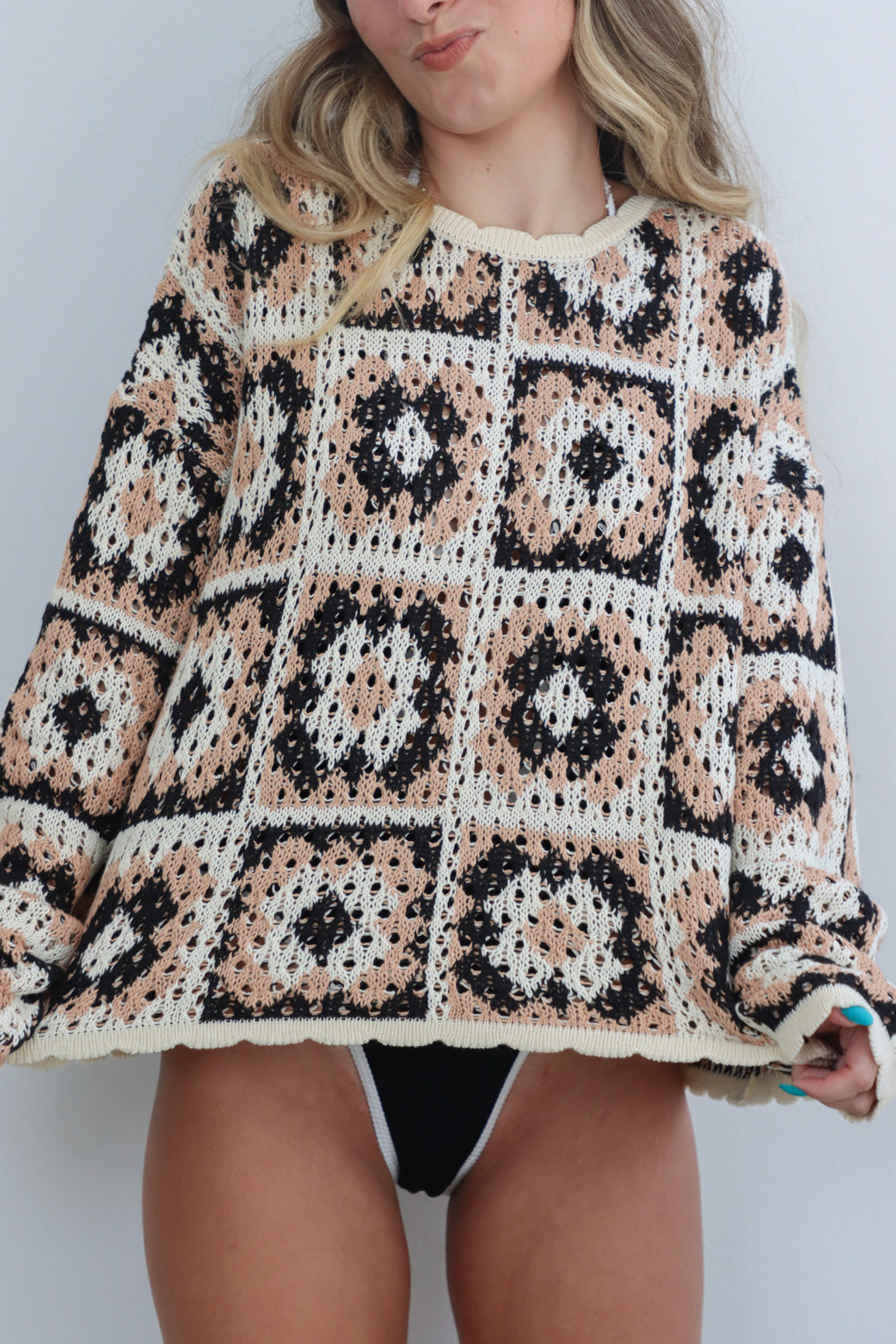 girl wearing tan, cream, and black crochet long sleeve sweater