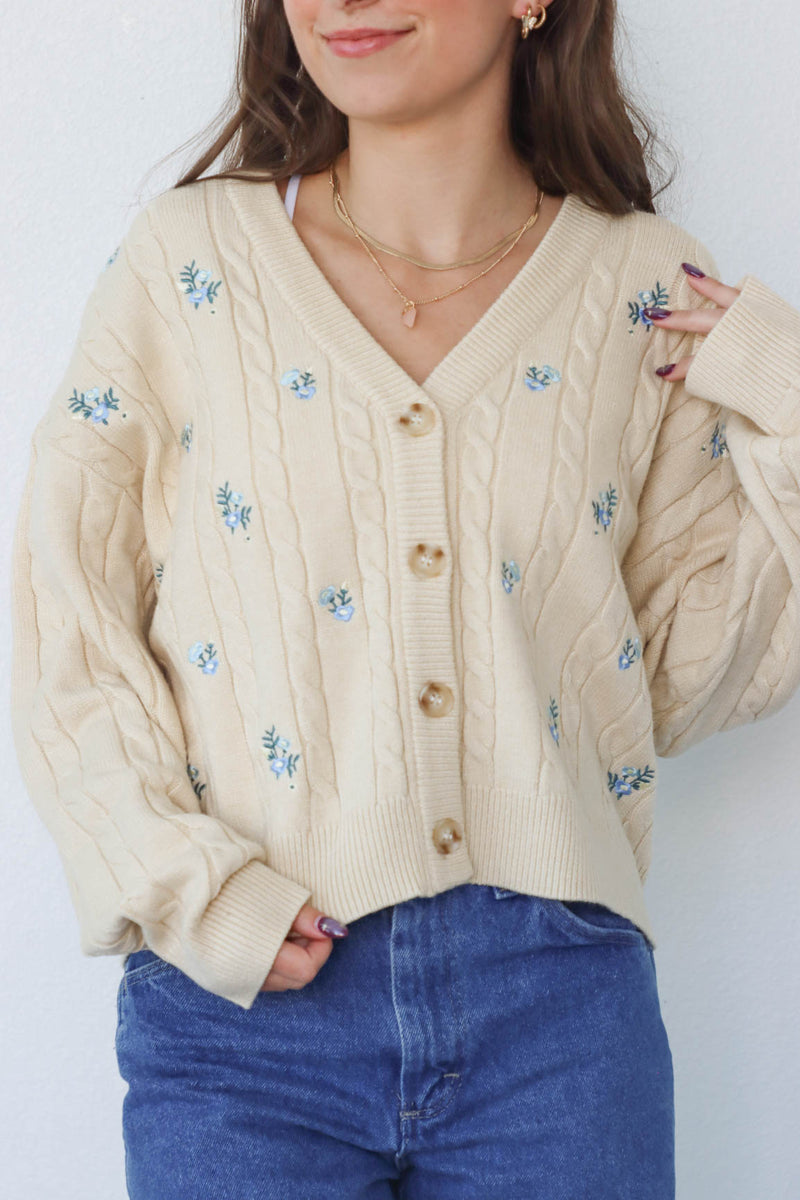 girl wearing cream knit cardigan with blue embroidered flowers