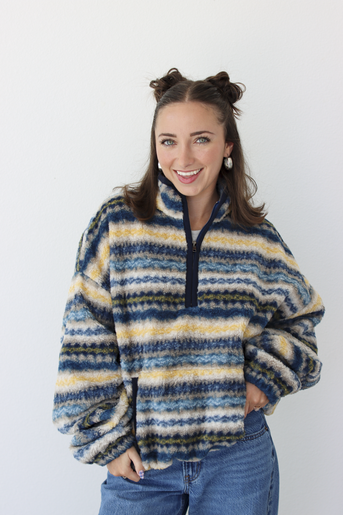 Woman wearing a blue sherpa quarter zip jacket with a pattern and blue denim jeans 