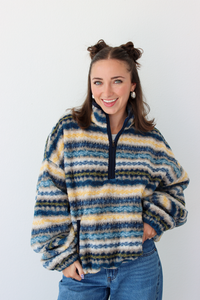 Woman wearing a blue sherpa quarter zip jacket with a pattern and blue denim jeans 