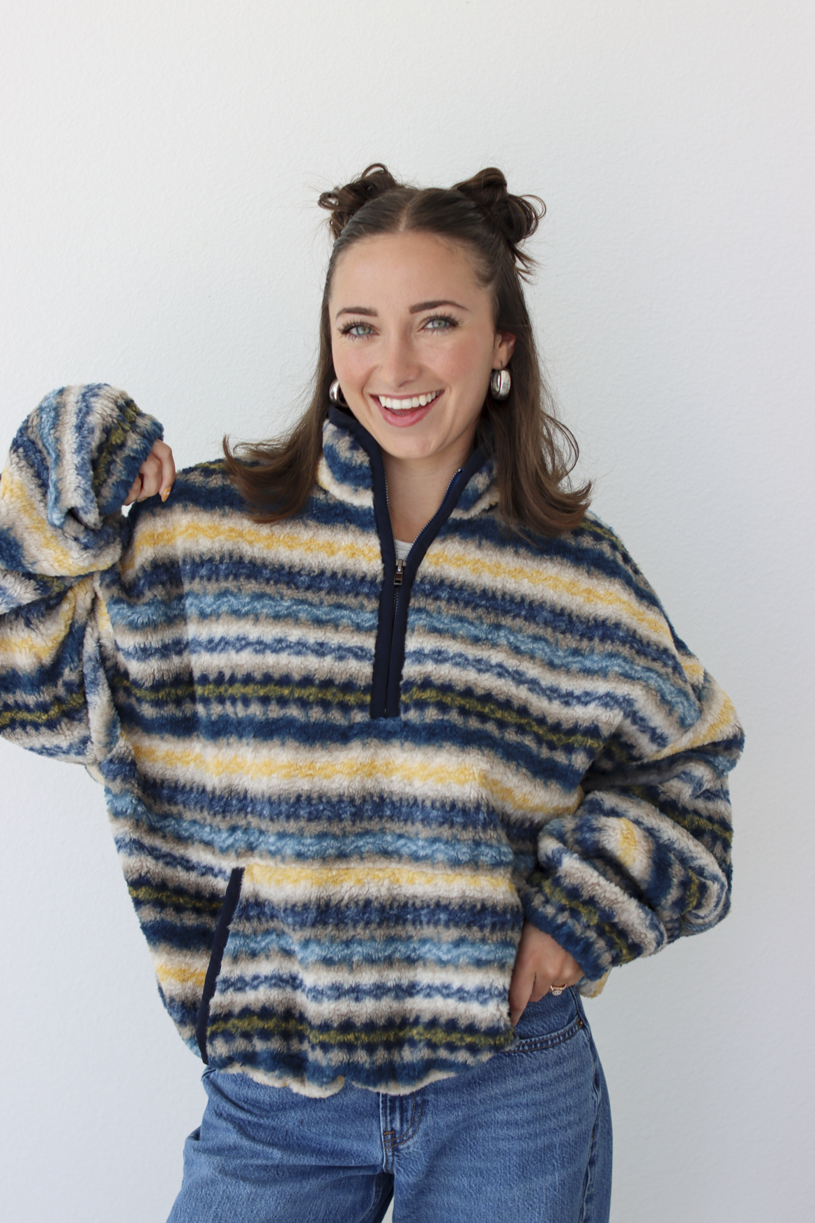 Woman wearing a blue sherpa quarter zip jacket with a pattern and blue denim jeans 