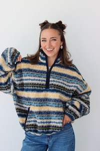 Woman wearing a blue sherpa quarter zip jacket with a pattern and blue denim jeans 