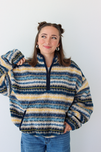 Woman wearing a blue sherpa quarter zip jacket with a pattern and blue denim jeans 