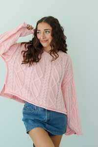 Woman wearing a pink knit sweater with a blue denim mini skirt 