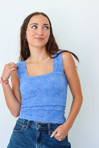 Woman wearing a blue sleeveless top with a white background