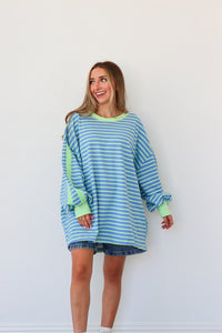 Woman wearing a blue and green striped dress against a white background