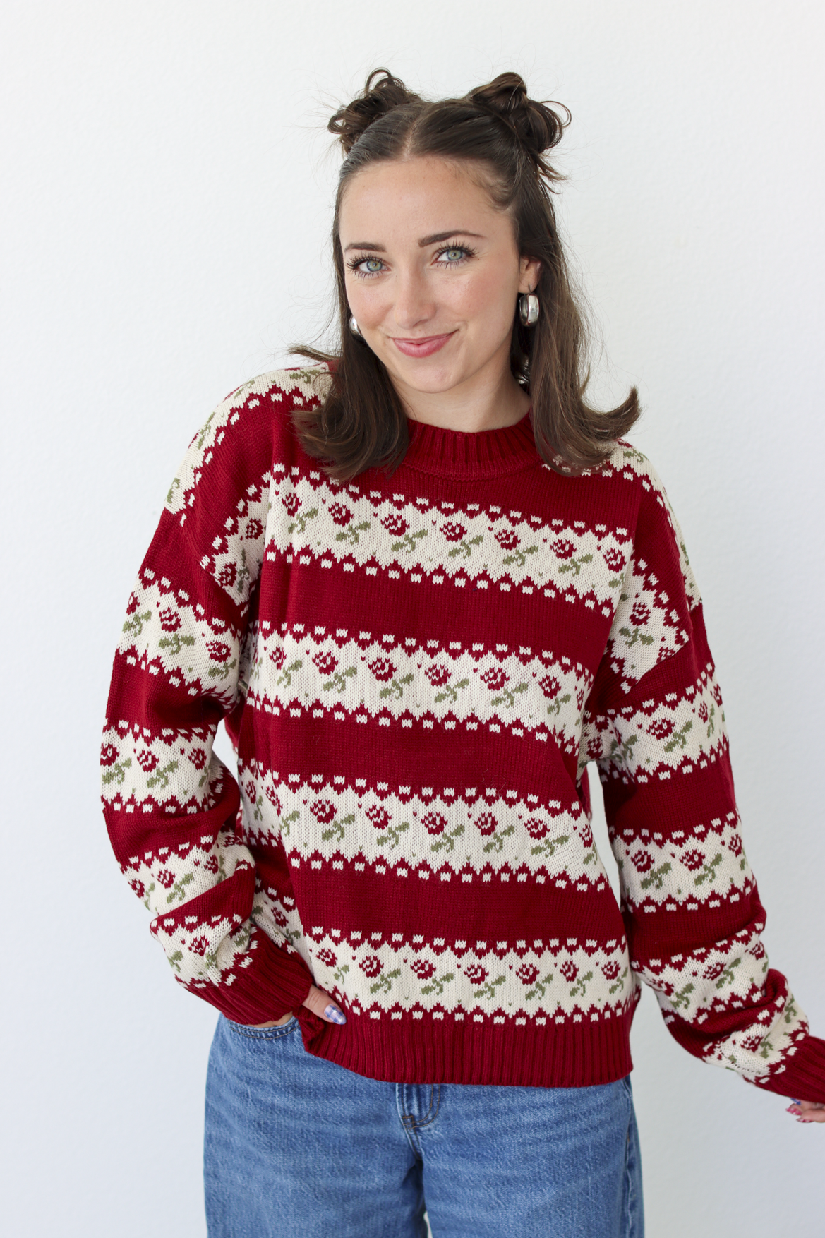 Woman wearing a red sweater with roses and blue denim jeans 