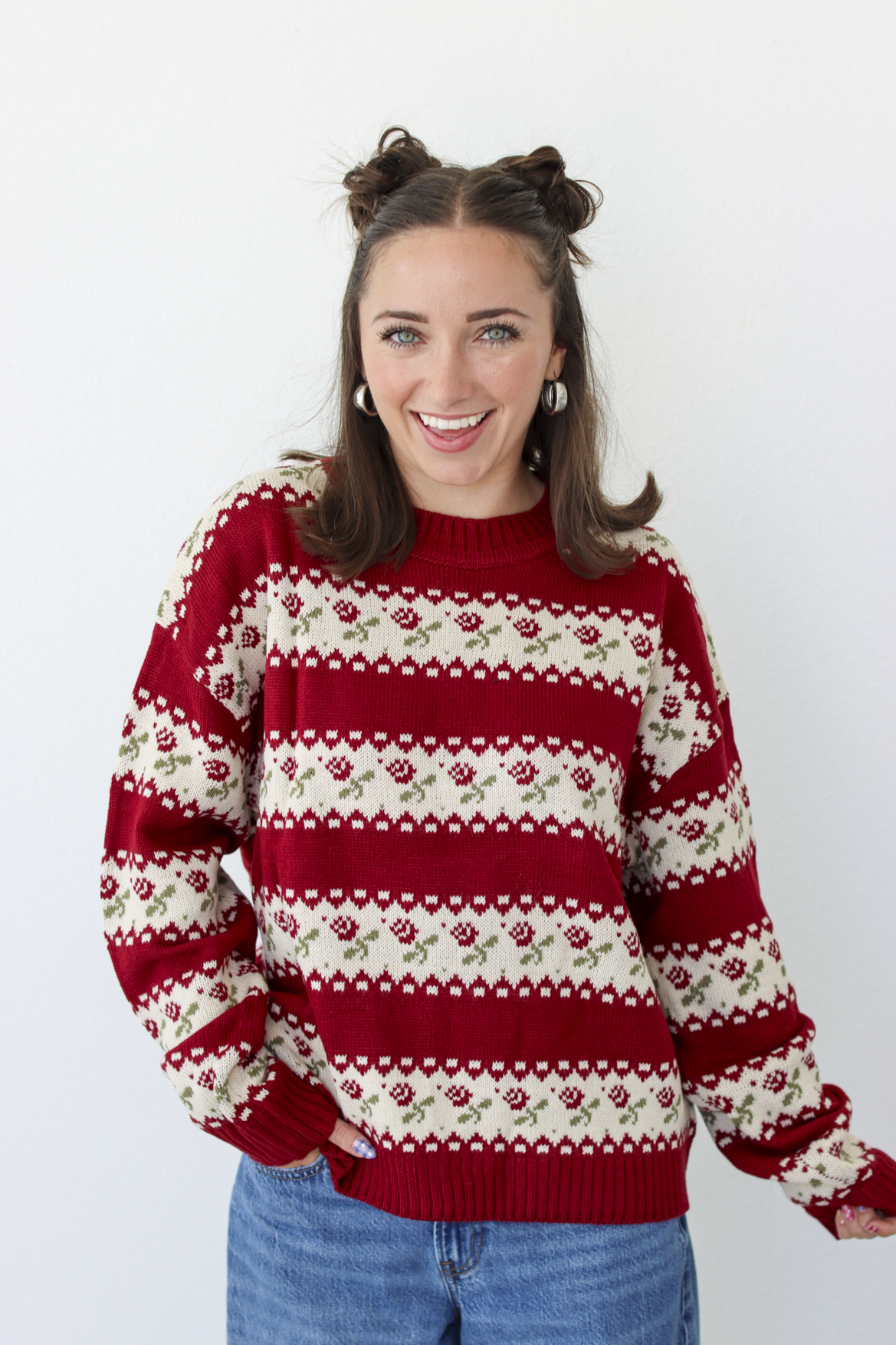 Woman wearing a red sweater with roses and blue denim jeans 