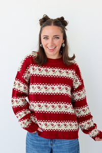 Woman wearing a red sweater with roses and blue denim jeans 